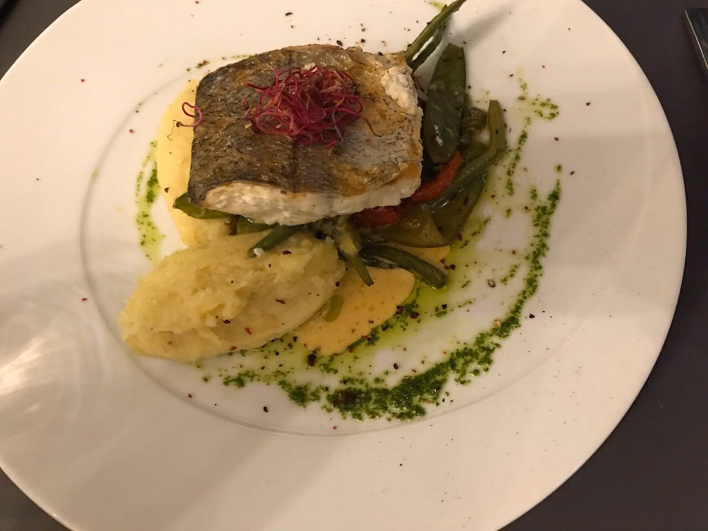 Gebratenes Kabeljaufilet mit knuspriger Haut auf Kartoffelpüree, dazu Bohnen und Zuckerschoten, heller Saucenspiegel und rote Kresse