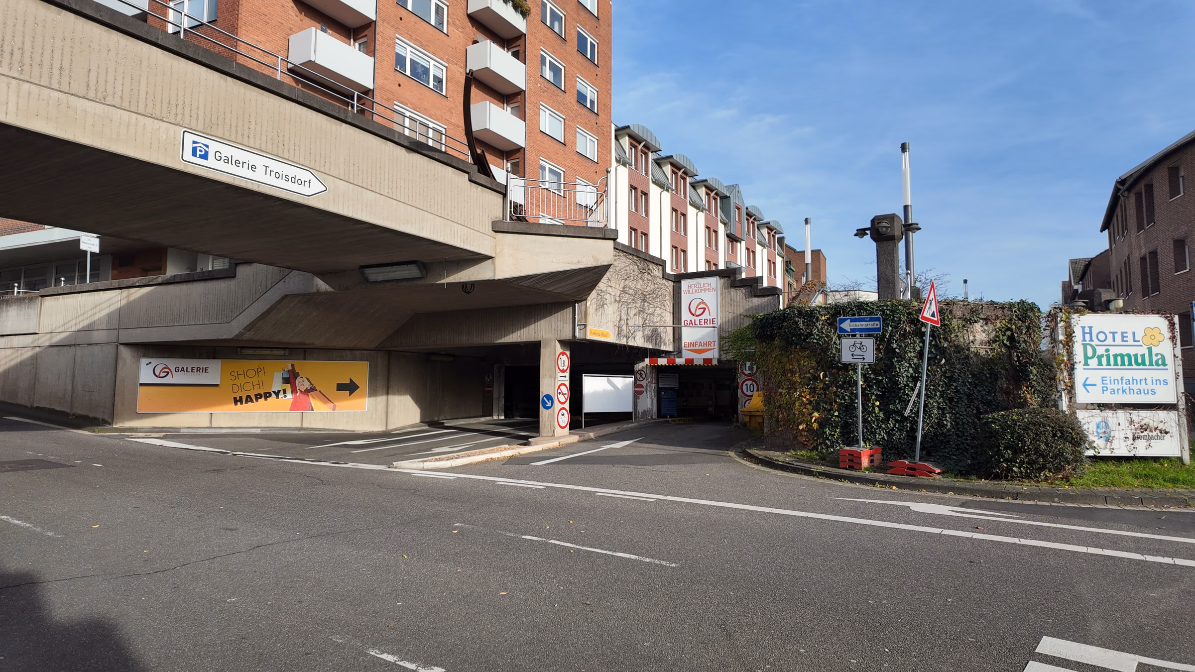 Entrance to the Galerie Troisdorf parking garage beneath the concrete canopy, with signpost and entry sign