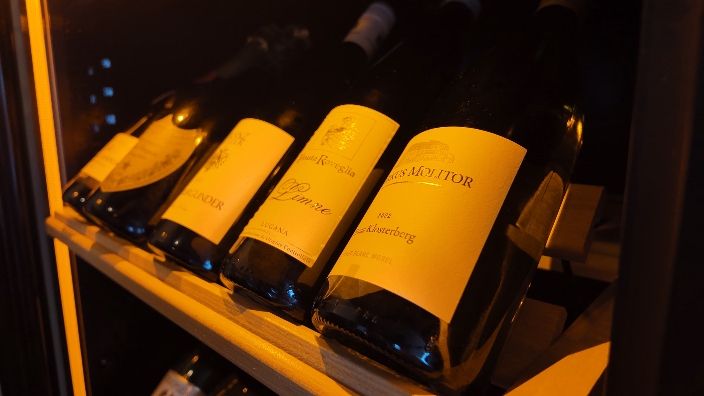 White wine bottles lying in the illuminated wine fridge at Restaurant Adria